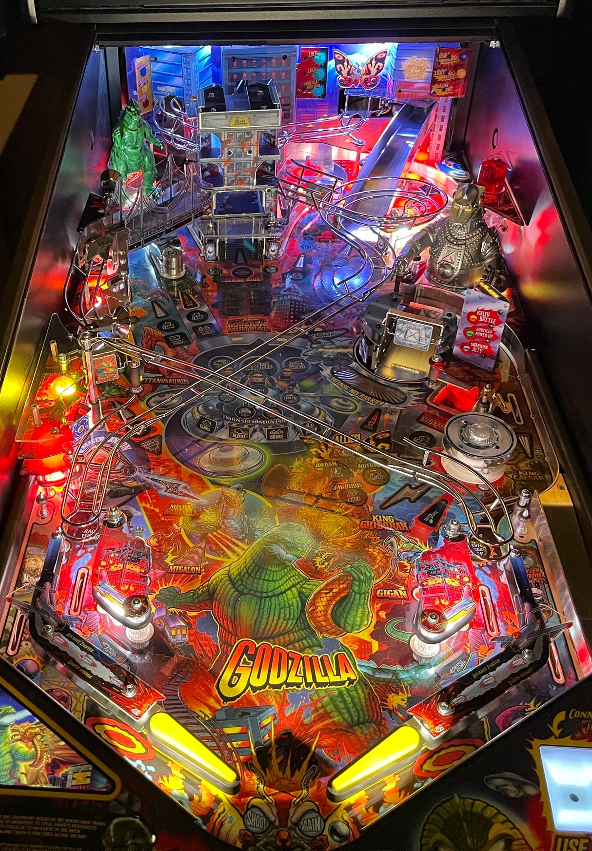 Pinball machine with 'Godzilla' branding, colorful lights, and detailed artwork.