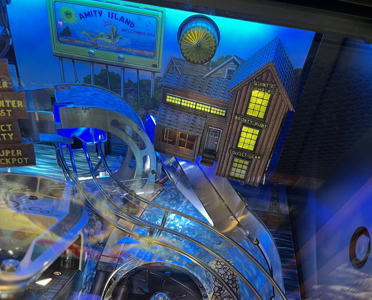 Pinball machine with colorful design and text, featuring a house and 'Amity Island' sign.