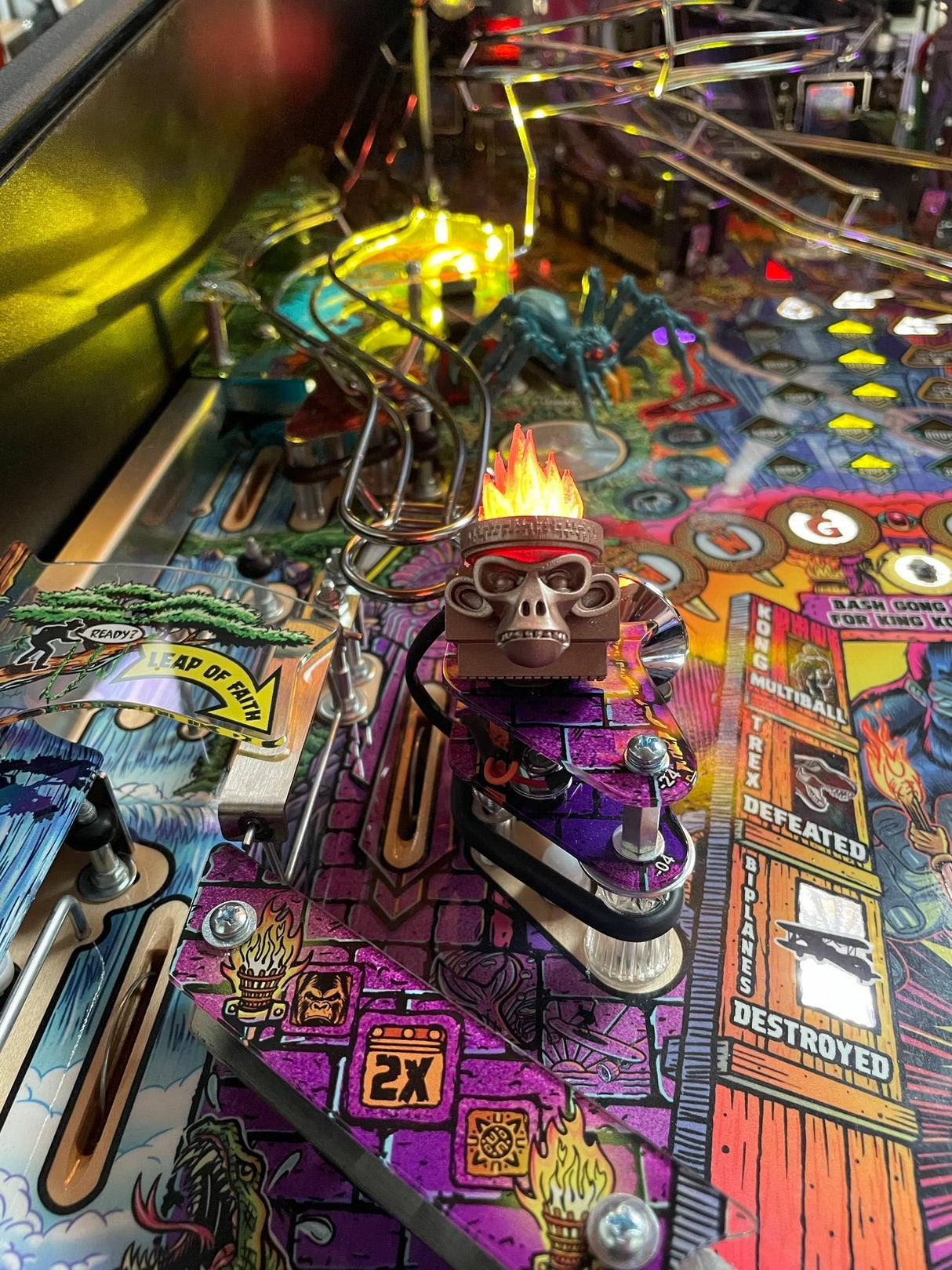 Close-up of a pinball machine with colorful artwork and a central figure.