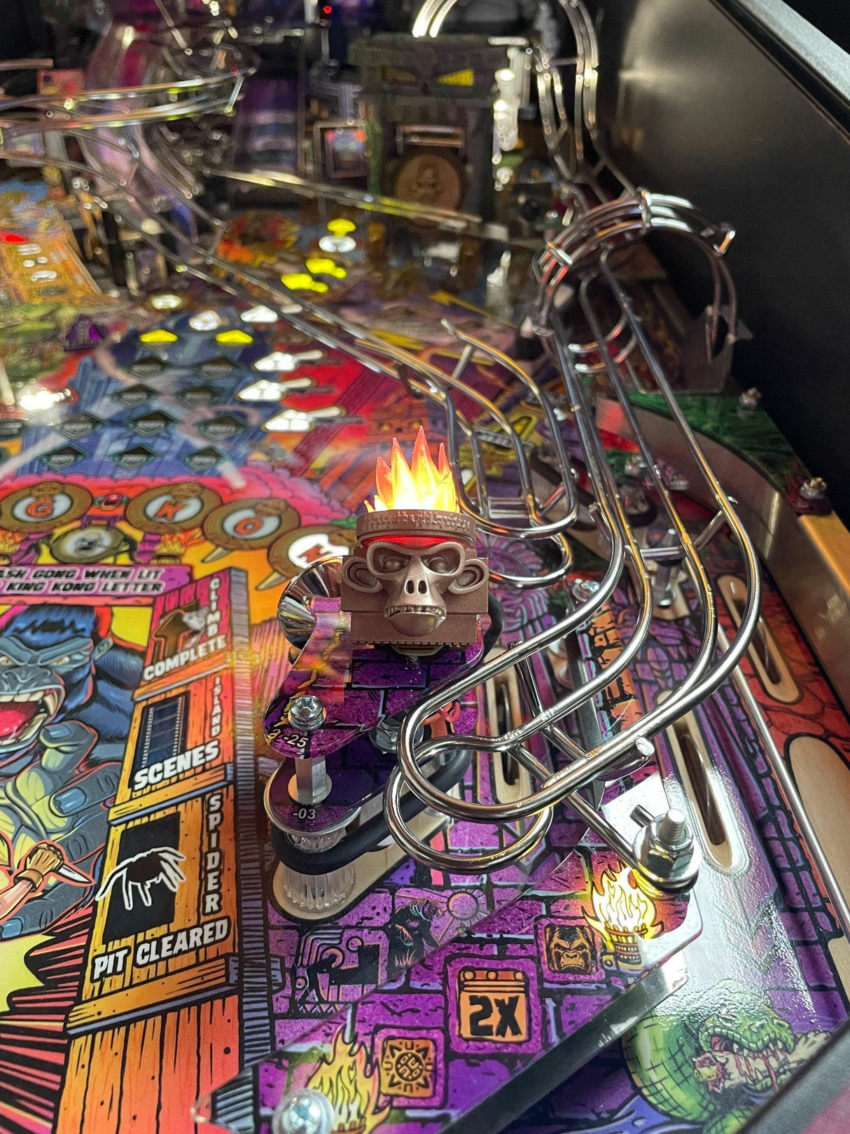 Close-up of a pinball machine with colorful artwork and a monkey head torch.