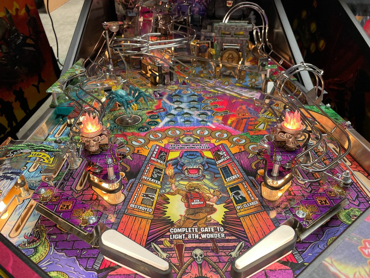 Colorful pinball machine with various components and artwork on a dark background