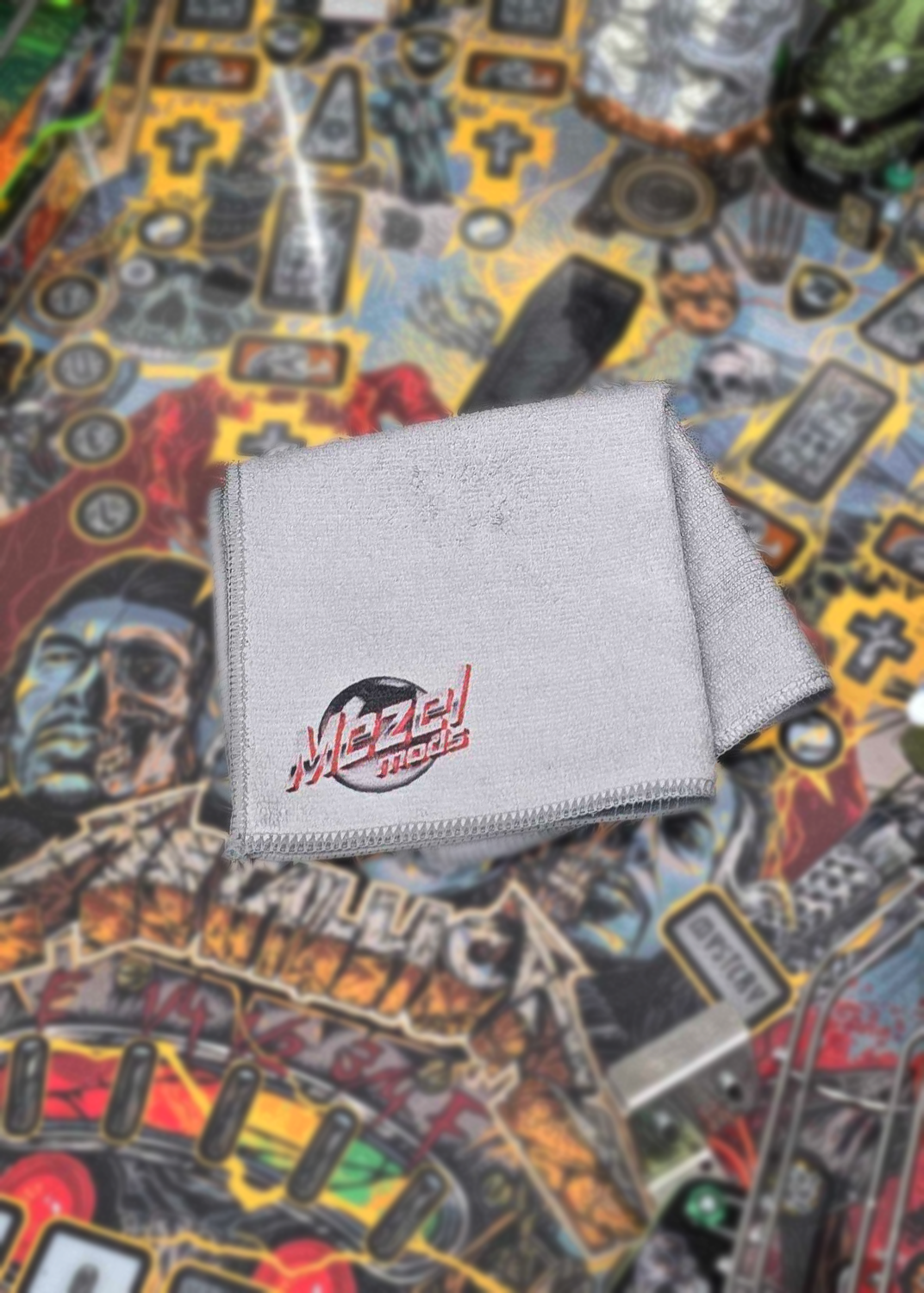 Gray towel with a logo on a colorful pinball playfield background