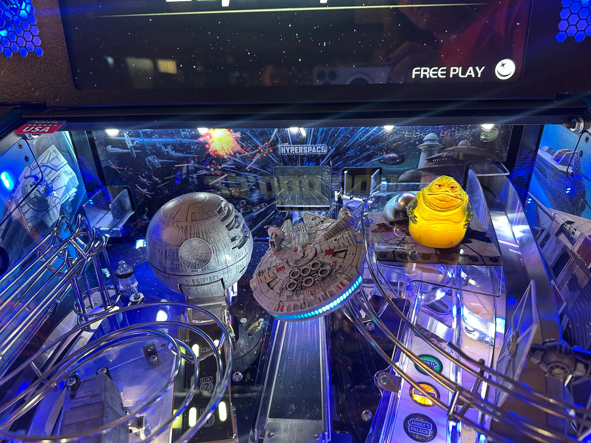 Pinball machine with Star Wars-themed decorations, including a Millennium Falcon and Death Star.