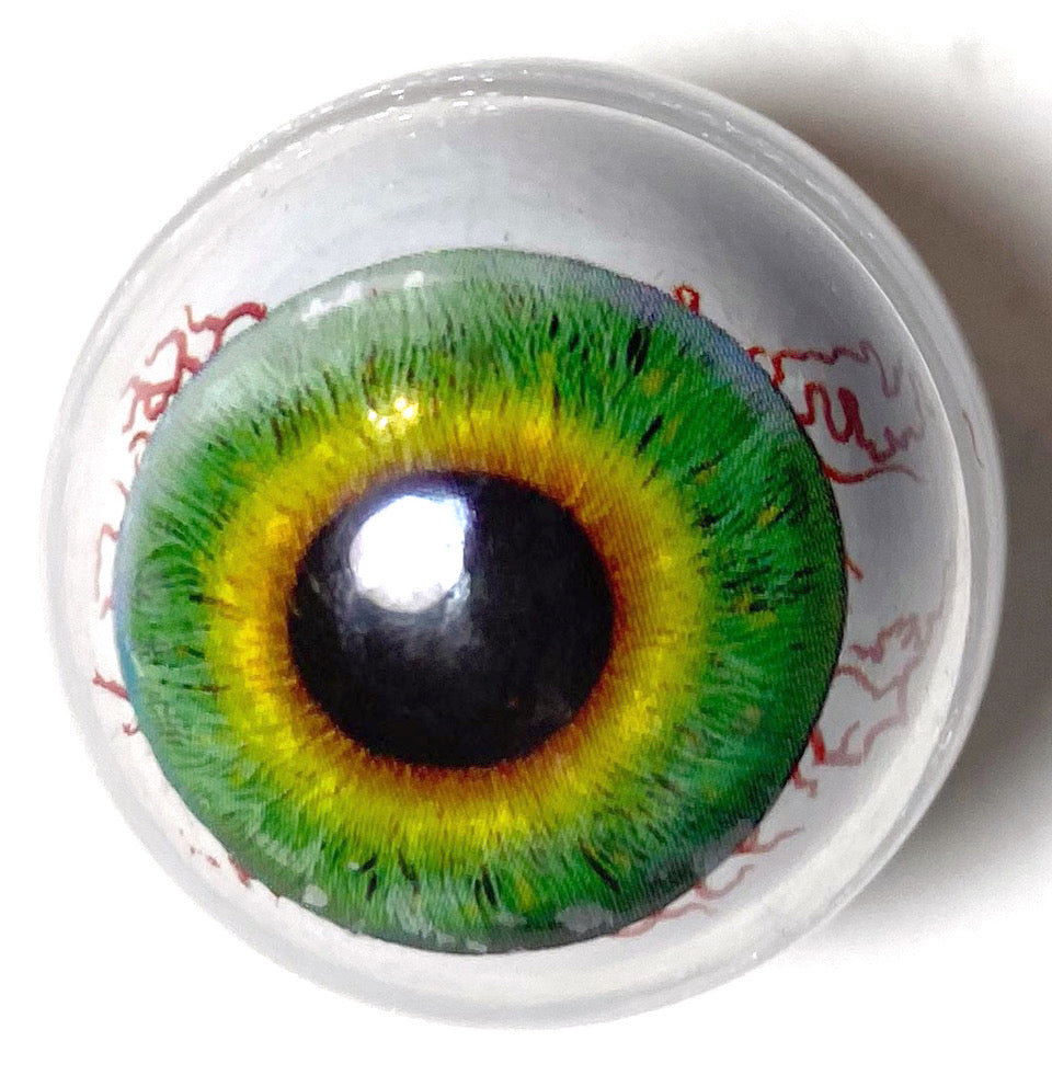 A ceramic pinball ball designed to look like a human eyeball with green iris and black pupil, set against a white background.