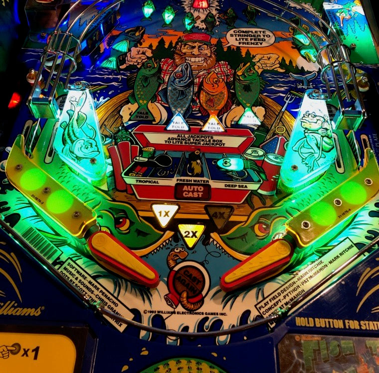 An overhead view of a pinball machine playfield with colorful protectors in place.