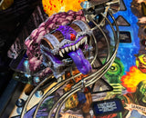 Close-up of a pinball machine with a detailed monster head chest sculpture and colorful background.