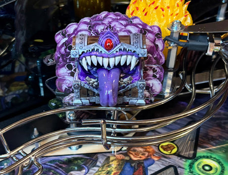 Toy figure of a purple creature with sharp teeth on a metallic stand.