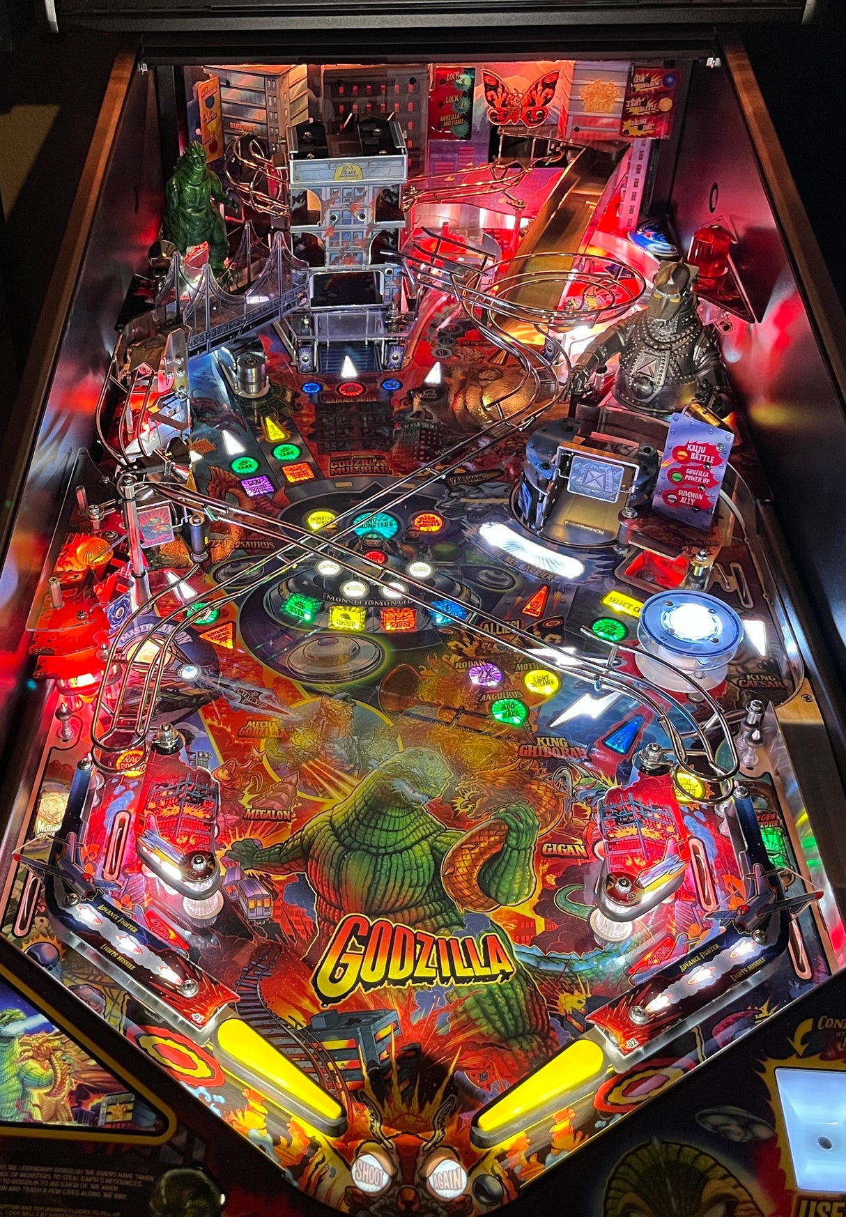 Pinball machine with 'Godzilla' theme, colorful lights, and detailed artwork.