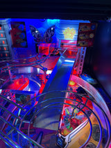 Pinball machine with colorful lights and artwork in an arcade setting