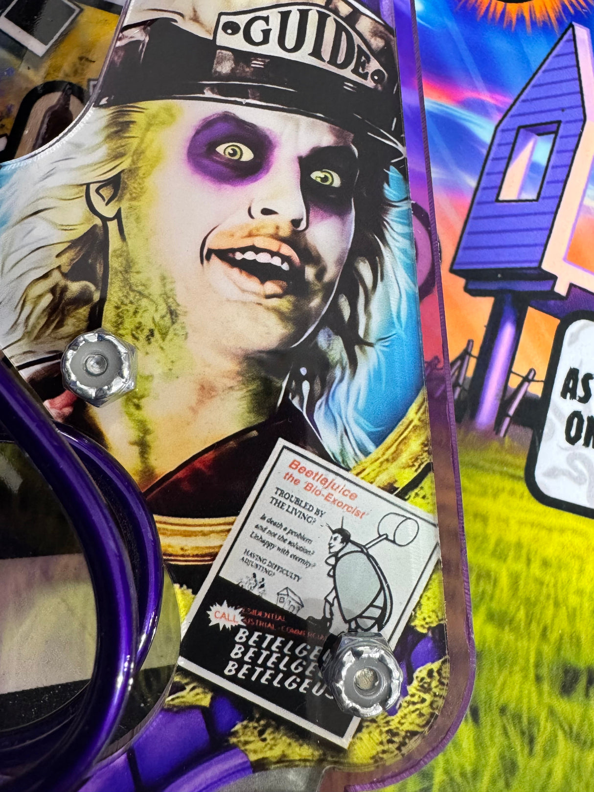 Installed left slingshot artwork featuring Betelgeuse's purple eye sockets, GUIDE hat, and mounting hardware.