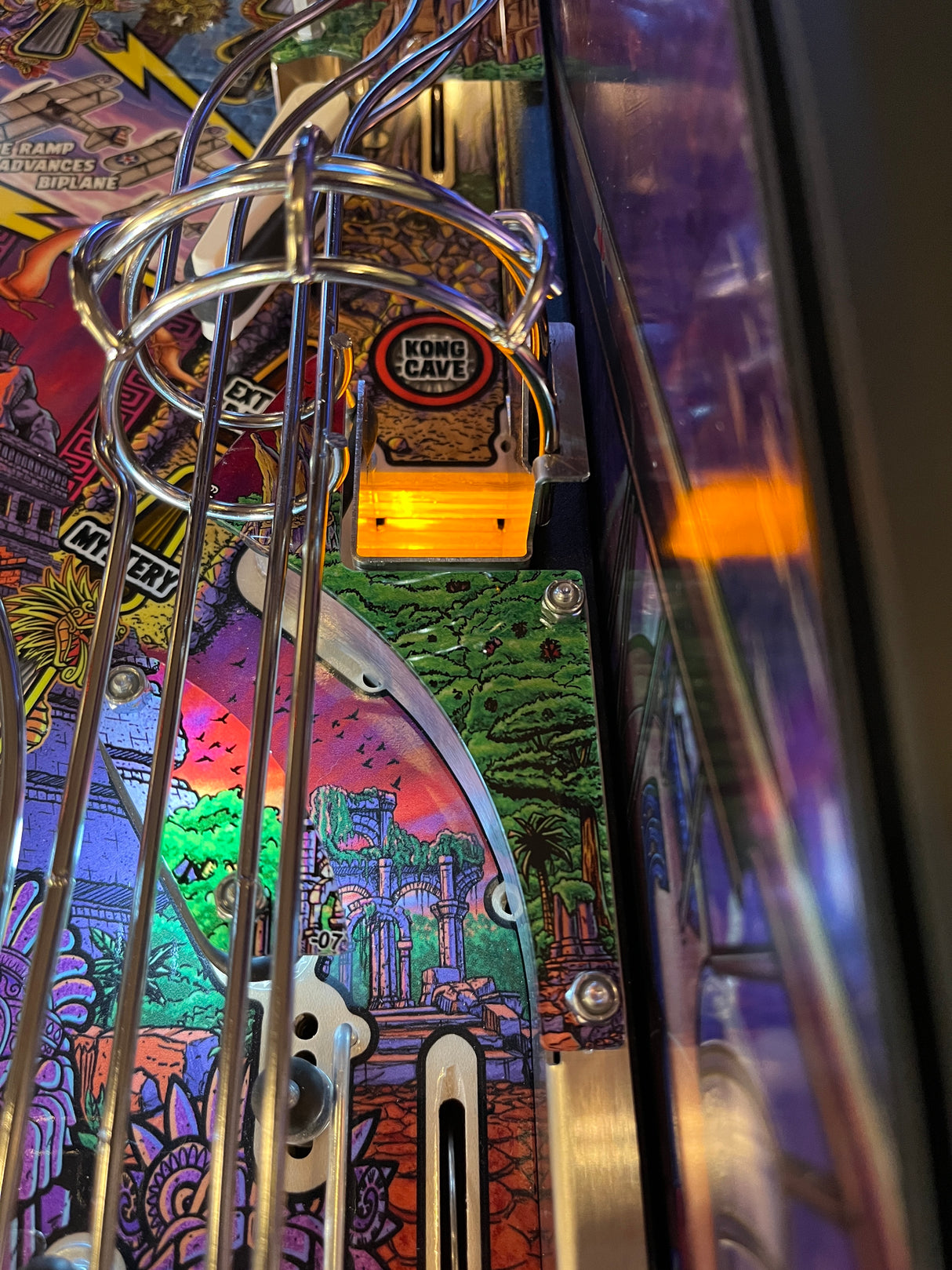 Close-up of a pinball machine with colorful artwork and a glowing light.