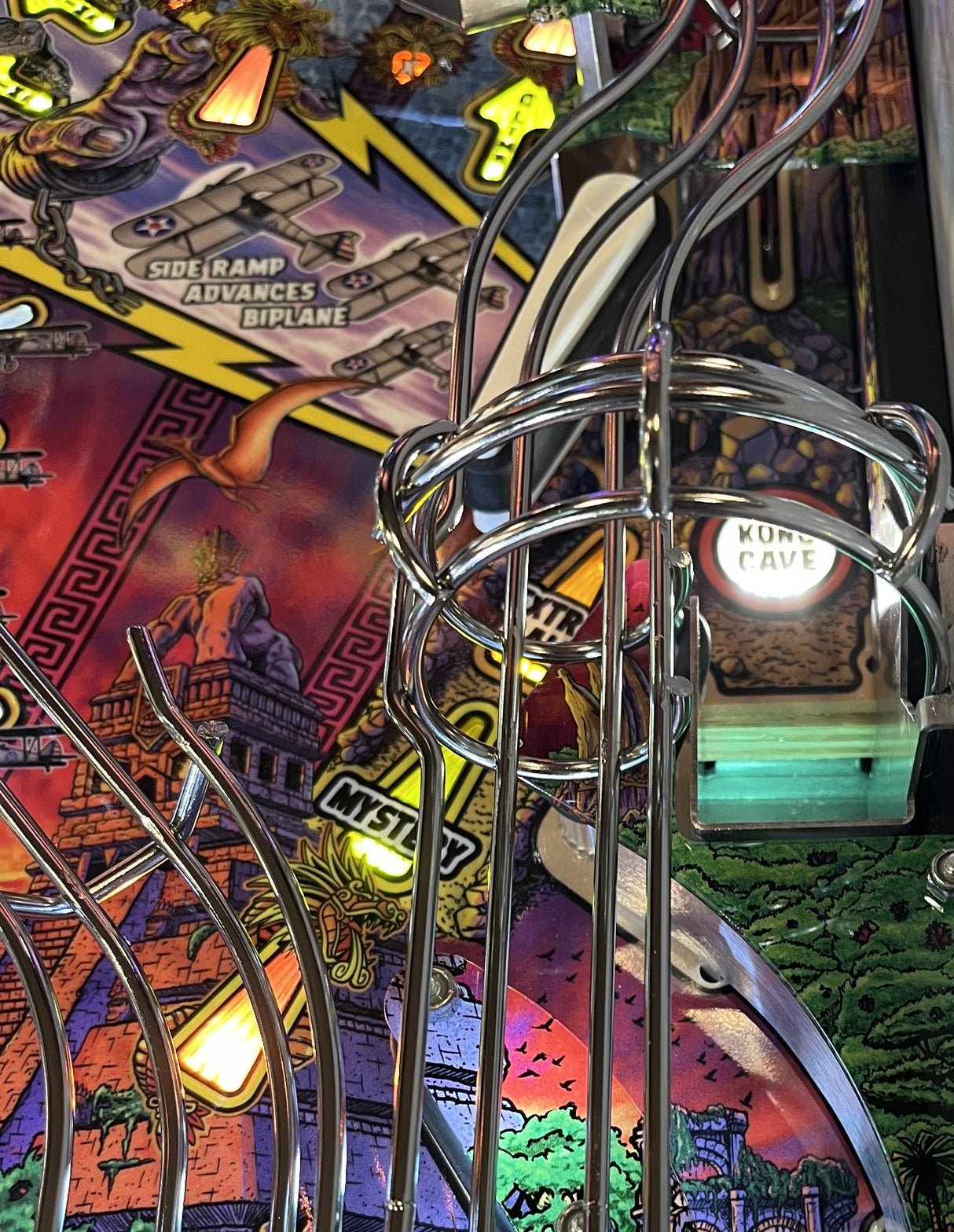 Close-up of a pinball machine with colorful artwork and metal components.