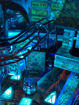 Close-up of a pinball machine with glowing blue lights and intricate details.