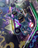 Close-up of a pinball machine with a blue monster figure on a colorful playfield.