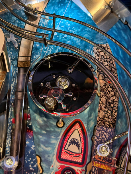 Close-up of a colorful and detailed reel on a pinball machine with a shark design on a blue background.