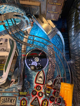 Close-up of a metal reel mod on a jawspinball machine with various components and stickers.