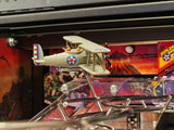 Model airplane on a pinball machine with colorful artwork in the background