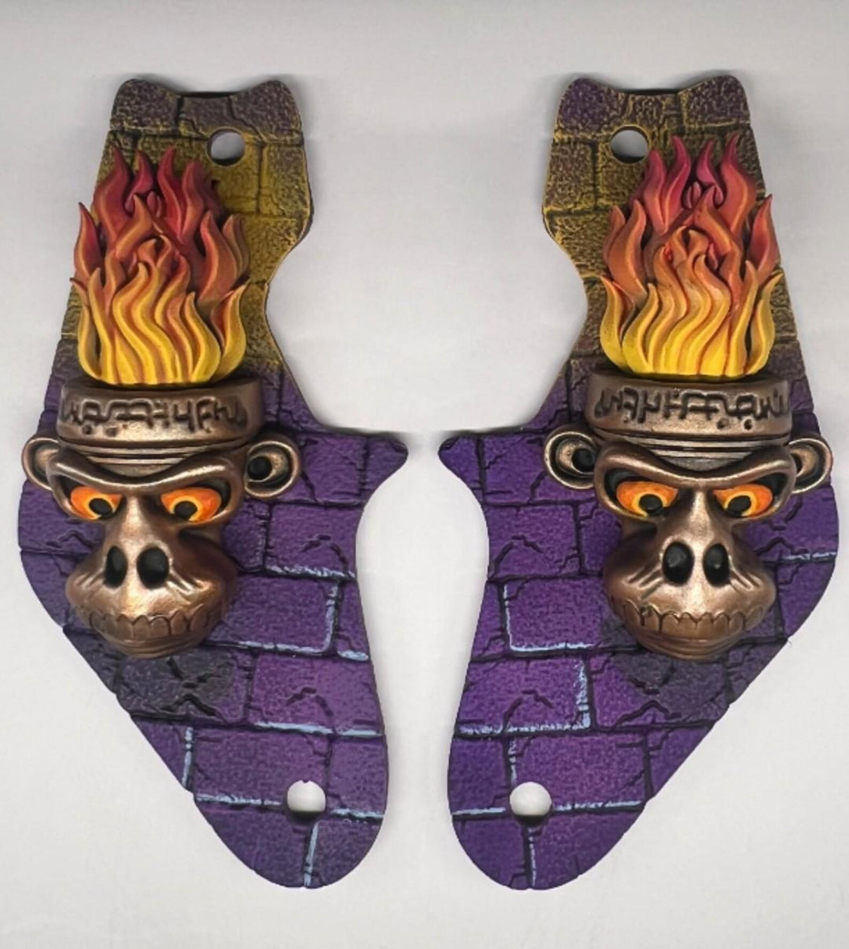 Pair of decorative toys with monkey head designs and flames on a white background