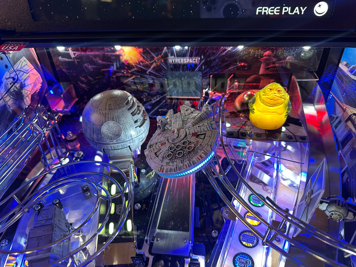 Pinball machine with Star Wars-themed decorations, including a Death Star and Millennium Falcon.