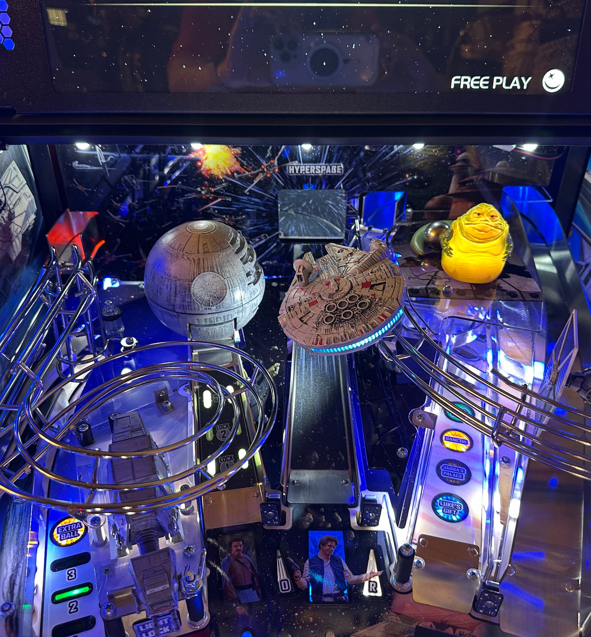 Pinball machine with Star Wars-themed decorations, illuminated ramp, including the Death Star and Millennium Falcon.